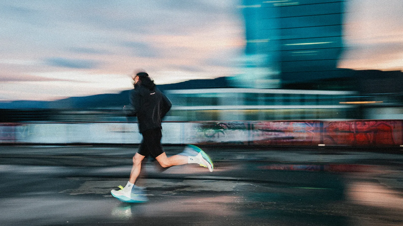 Motion blur of runner passing graffiti wall with city skyline at golden hour